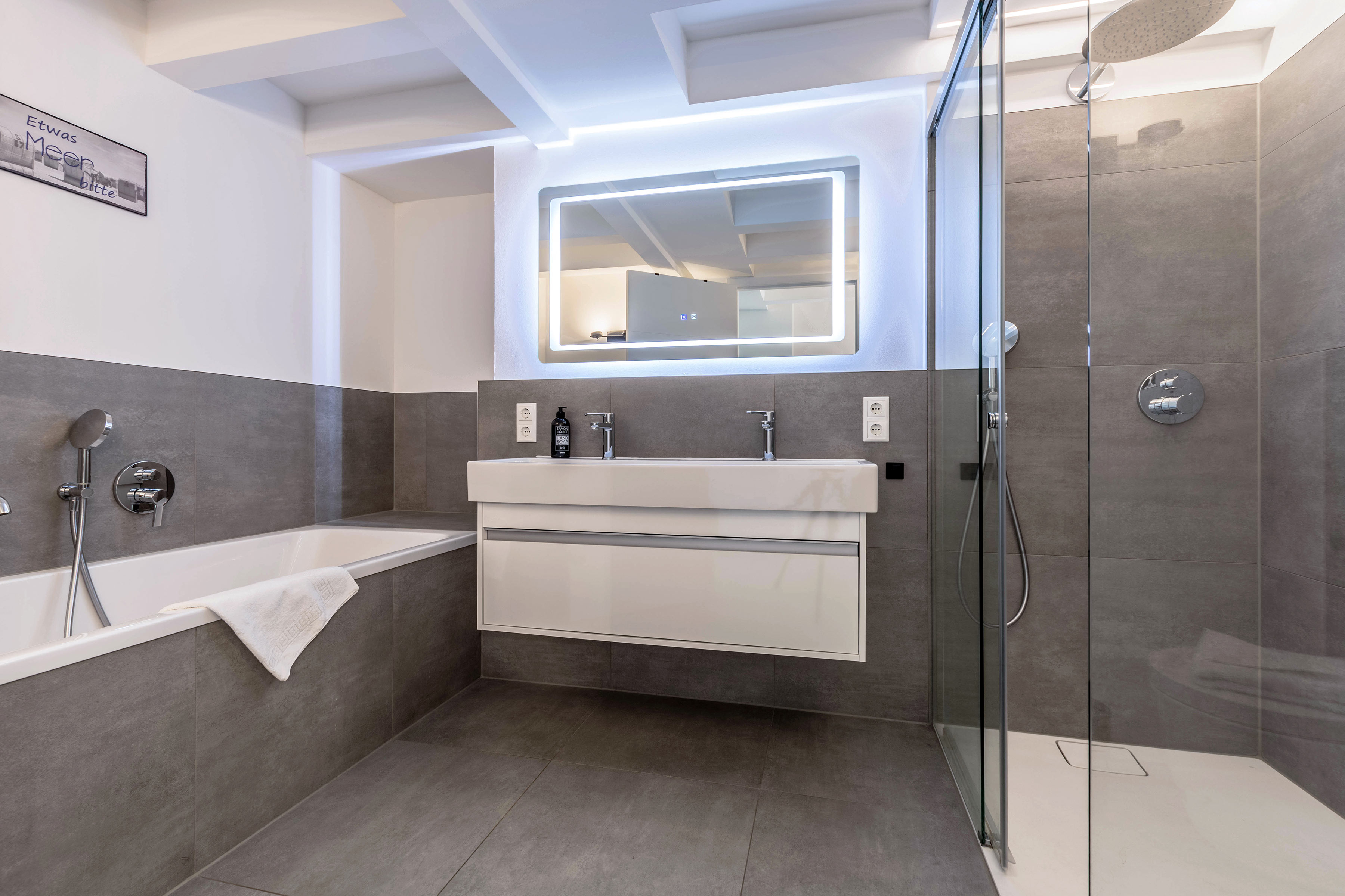 Badezimmer mit Wanne, Waschtisch und Spiegel